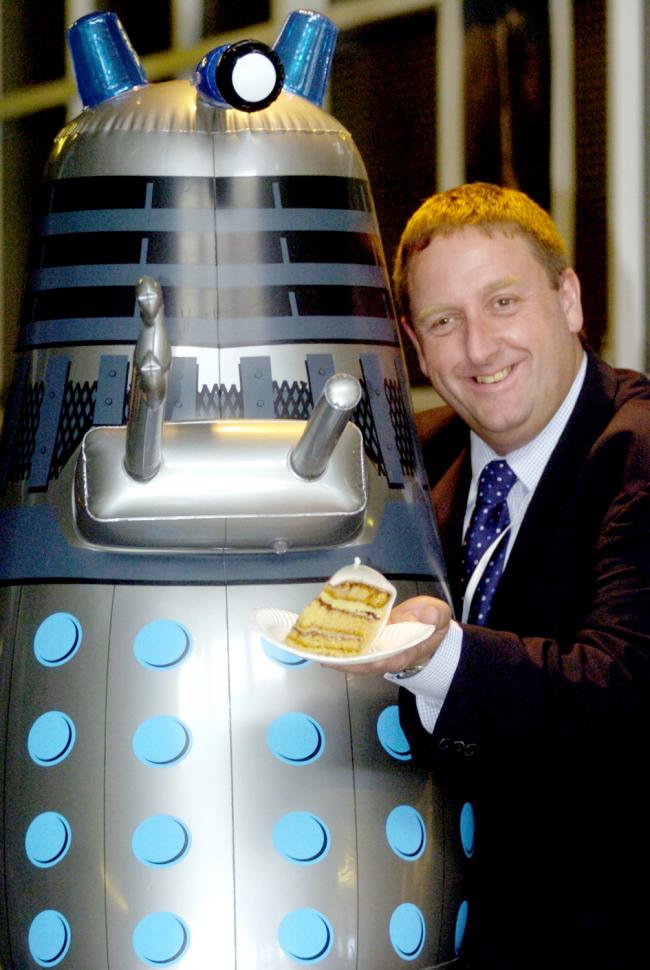 PIECE OF CAKE:  Ken Moss, Manager of Space-port offers a slice of  birthday cake to a local Dalek