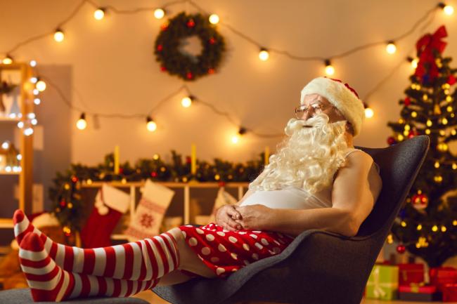 Santa watching TV with his feet up. Credit: Canva